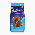 A package of Bahlsen Milk Chocolate Akora gingerbread hearts on a clean white background. The packaging is dark blue and light blue with white text and illustrations of snowflakes, showing two heart-shaped cookies, one whole and one broken to reveal the filling.