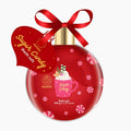 A red Christmas ornament-shaped bath salt container with a gold cap and a red ribbon bow, featuring a heart-shaped tag that reads 'Sugar Candy Bath salt' and 'Aurora' branding. The ornament is decorated with pink candy cane motifs and a mug illustration with whipped cream.