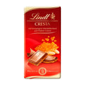 Packaging of Lindt Premium Cresta milk chocolate bar, 100 g, displaying the bar and ingredients like hazelnuts and almonds on a red background.