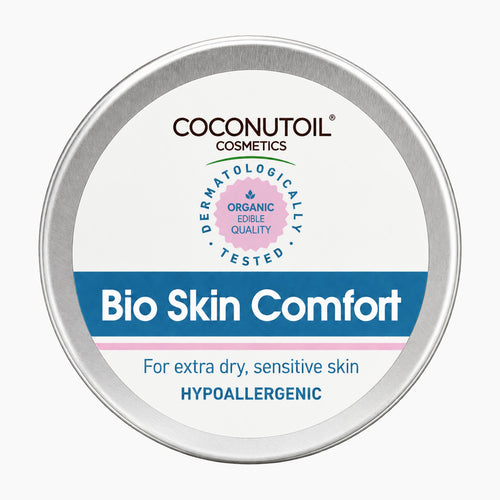 A round silver metal tin of Coconutoil Cosmetics Bio Skin Comfort hypoallergenic body butter, featuring a white label with blue and pink accents, on a light gray background.