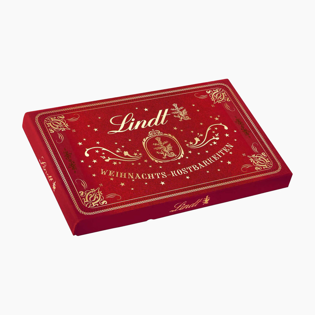 Lindt Christmas Treasures Velvet Pralines box in red velvet with gold foil detailing, shown at an angle on a white background.