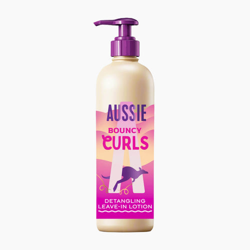 A bottle of Aussie Bouncy Curls Detangling Leave-In Lotion with a cream-colored body, a purple pump dispenser, and a pink and purple label featuring a kangaroo graphic.