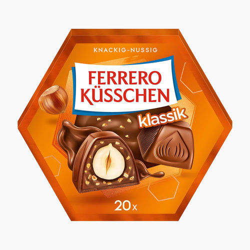 A hexagonal package of Ferrero Küsschen Classic chocolate pralines, featuring an orange design with illustrations of hazelnuts and chocolate pieces, on a light gray background.