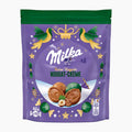 A stand-up pouch of Milka Feine Kugeln Fine Pralines Nougat Cream chocolate, featuring a purple background with a green top band, decorative birds, stars, and illustrations of the chocolate pieces inside.