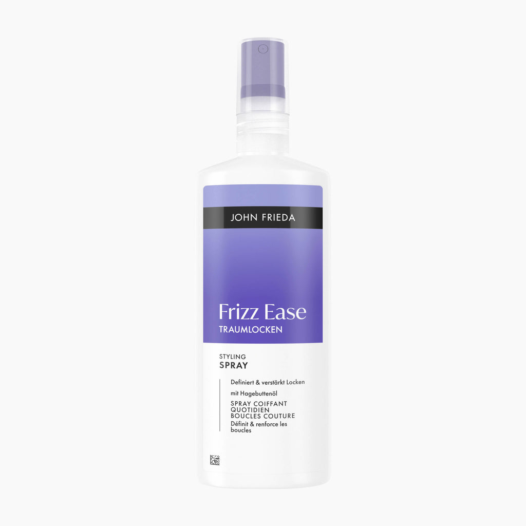 A bottle of John Frieda Frizz Ease Dream Curls Styling Spray hair smoothing treatment, featuring a white bottle with a lavender purple label and spray nozzle, set against a plain white background.