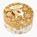 A round Lindt Goldstücke Gold Nuggets Christmas-themed pralines gift box with a gold lid decorated with white reindeer, snowflakes, and stars, topped with a gold glitter bow. The side of the box is white with gold and silver snowflakes and German text.