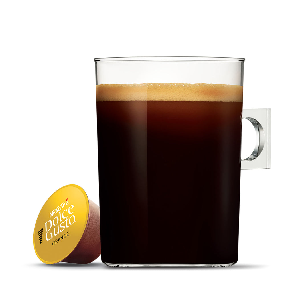 Nescafé Dolce Gusto coffee capsule next to a glass of coffee on a white background