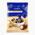 A bag of Riegelein Gubor Eierlikör-Trüffel Egg Liqueur Truffles milk chocolate truffles, featuring a festive blue and gold holiday design with a bowl of wrapped chocolates and chocolate pieces on a light wood background.