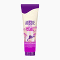 A squeeze tube of Aussie Work That Curl Leave-In Cream, featuring a purple and cream design with a kangaroo graphic, on a light gray background.