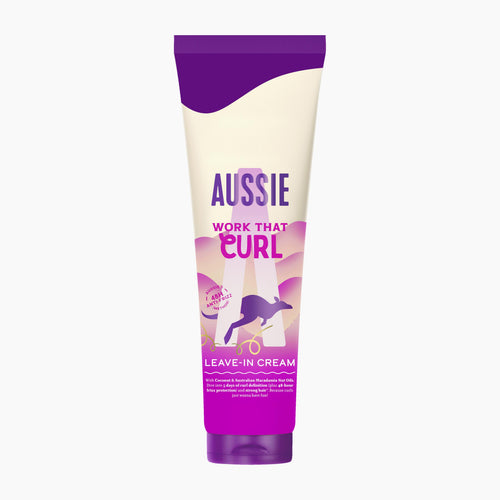 A squeeze tube of Aussie Work That Curl Leave-In Cream, featuring a purple and cream design with a kangaroo graphic, on a light gray background.