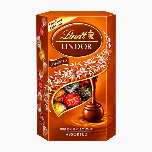Lindt Lindor Assorted Autumn Limited Edition chocolate pralines in a orange cardboard box with gold and white decorative graphics, on a light gray background.