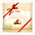 Zentis Traditions Marzipan Potatoes in a beige gift bag with a red ribbon, featuring product imagery of marzipan almonds and cookies, with Fairtrade and Vegan logos at the bottom.