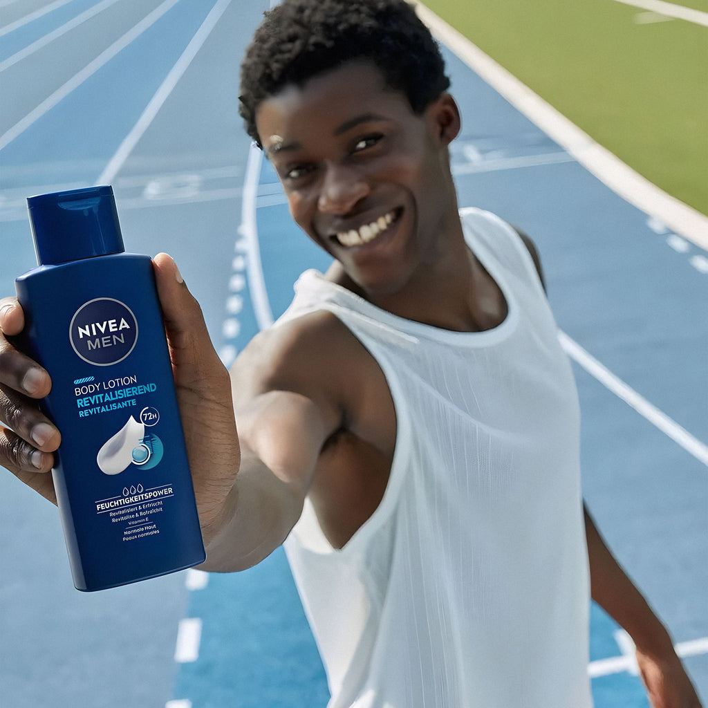 Person holding a Nivea Men body lotion bottle on a track background