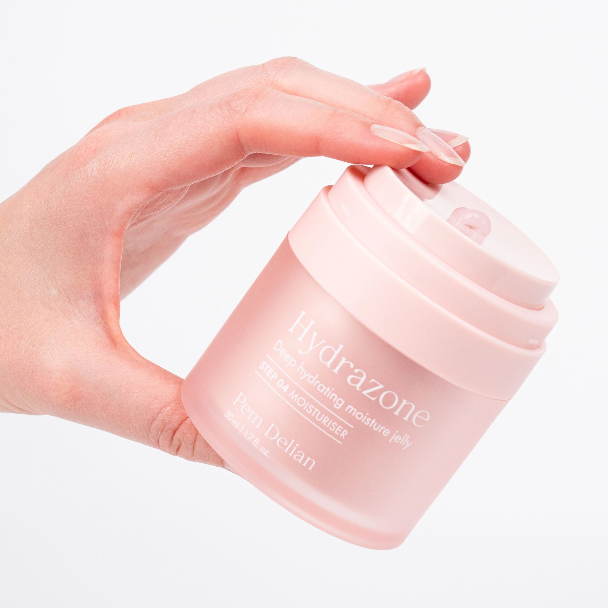 Hand holding a pink jar of Hydrazone cream against a light background