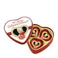 A heart-shaped tin containing three individually wrapped heart-shaped pralines with dark chocolate coating, pistachio marzipan, and cream truffle filling.