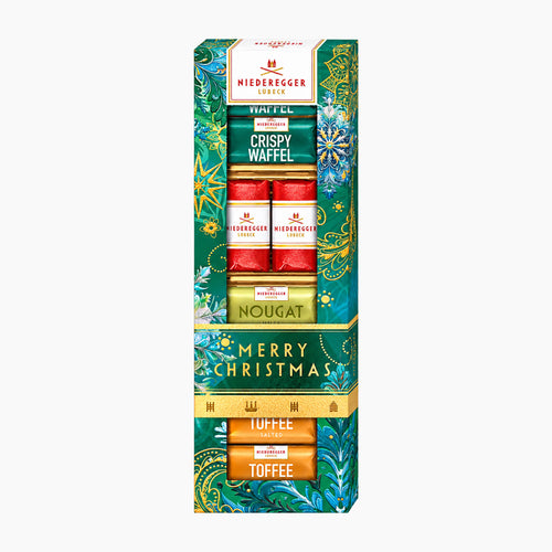 Niederegger Master Selection Merry Christmas chocolate pralines gift set in a tall decorative box, featuring Crispy Waffel, Marzipan, Nougat, and Toffee chocolates with festive green, red, and gold holiday packaging.