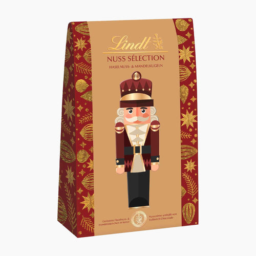 Lindt Nut Selection hazelnut and almond pralines in a decorative retail box featuring a nutcracker illustration and red-and-gold holiday patterned sides.