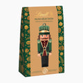 Lindt Nut Selection Pistachio & Hazelnut chocolate pralines bag box, featuring a festive green and gold patterned design with a central illustration of a nutcracker on a light gray background.