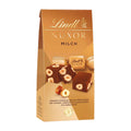 Packaging of Lindt Nuxor Milk chocolate pralines with visible chocolate cubes and hazelnuts, against a beige background.
