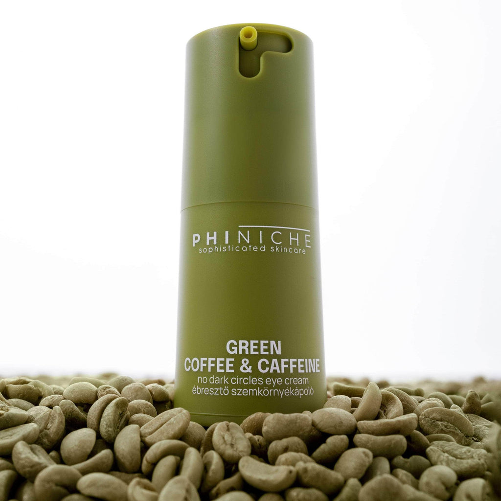 Eye cream bottle labeled 'Green Coffee & Caffeine' by Phiniche on a bed of coffee beans.