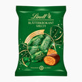 Lindt Blätterkrokant Milch Pine Cones with Flaky Brittle milk chocolate pralines packaging on a plain white background, featuring the Lindt logo and illustrations of wrapped chocolates and a cut-open chocolate piece.