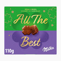 A 110g box of Milka 'All The Best' chocolate pralines, featuring a split green and purple design with gold lettering and clover motifs.