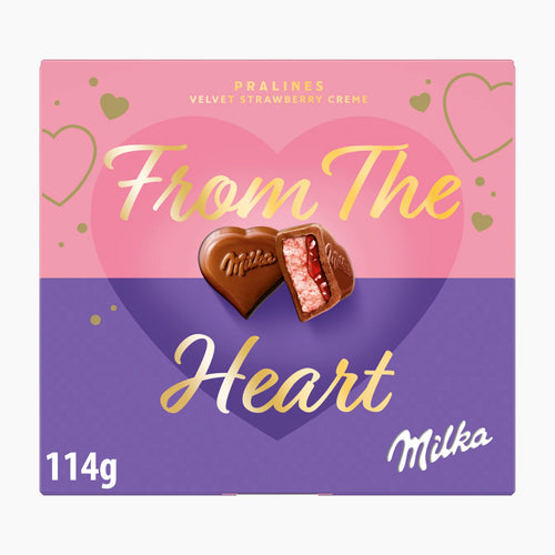 A square box of Milka Pralines Velvet Strawberry Creme, featuring a pink and purple heart design with gold lettering that reads 'From The Heart' and two heart-shaped pralines on the front.