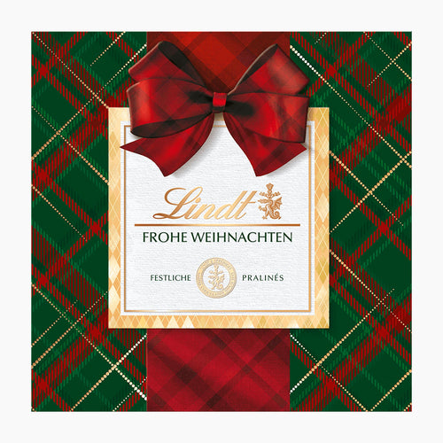 Lindt Karo Royal chocolate pralines box with a large red bow, set against a green and red tartan plaid background.