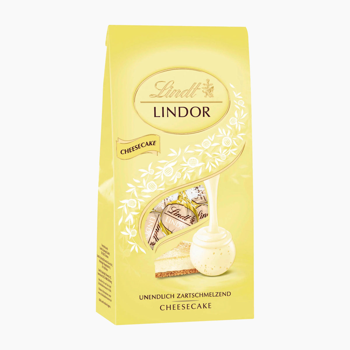 A 100g bag of Lindt Lindor Cheesecake white chocolate pralines in a pale yellow bag with white floral details and a photo of the filled chocolate pieces.