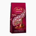 A 100 gpackage of Lindt Lindor Double Chocolate in a deep burgundy stand-up bag with gold and white branding, a decorative swirl, and an illustration of a chocolate praline.