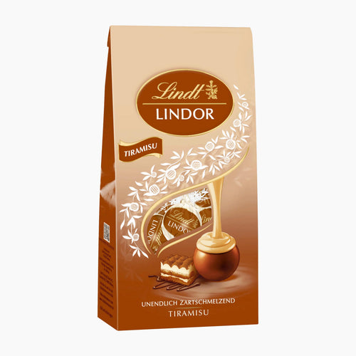 A 100g pack of Lindt Lindor Tiramisu chocolate pralines, featuring a beige and brown stand-up bag with white floral graphics, a gold-dripping motif, and an illustration of a chocolate piece with a slice of a tiramisu.