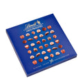 A box of Lindt Mini Pralines, featuring various mini chocolate confections, including almonds, caramel, hazelnut, macchiato, nougat, orange, pistachio, and marzipan, on a blue background.