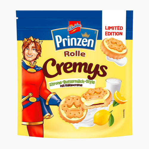 A package of Prinzen Rolle Cremys lemon buttermilk style sandwich cookies, featuring a yellow and blue bag with an illustration of the brand's mascot in a red royal costume, alongside images of the cookies and lemons.