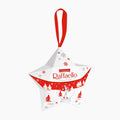 Raffaello Little Star Christmas ornament shaped like a star, featuring a red hanging loop, red and white winter-themed printed design with snowflakes and pine trees, and a small Ferrero praline visible inside.