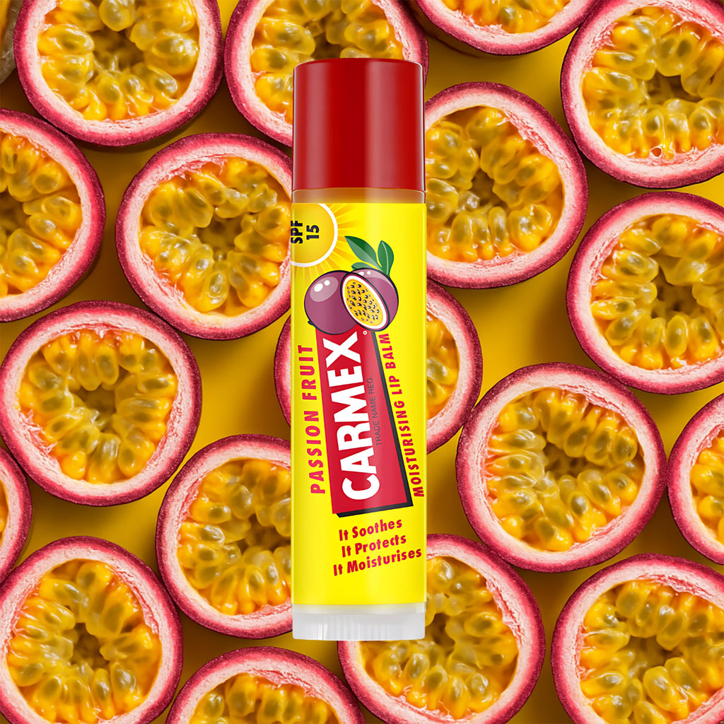 Carmex Passion Fruit lip balm stick surrounded by passion fruit slices on a yellow background