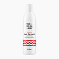 A white bottle of The Silky Way Hair Growth Shampoo with black and red text and a red wavy stripe pattern near the bottom, shown on a light gray background.