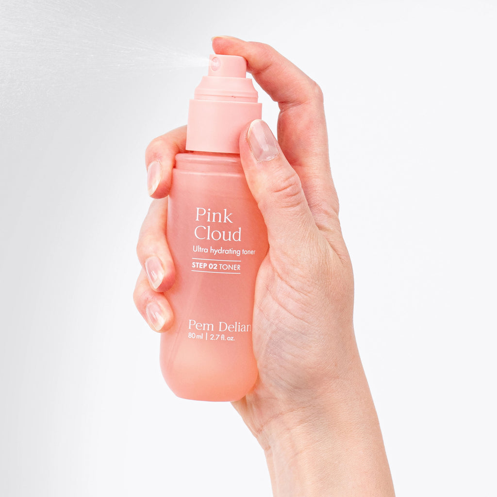 Hand holding a Pem Delian Pink Cloud toner bottle against a light gray background