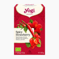 A box of Yogi Organic Spicy Strawberry spiced and fruit tea box on a light gray background. The packaging is primarily red with illustrations of strawberries, red chili peppers, hibiscus flowers, and green leaves.